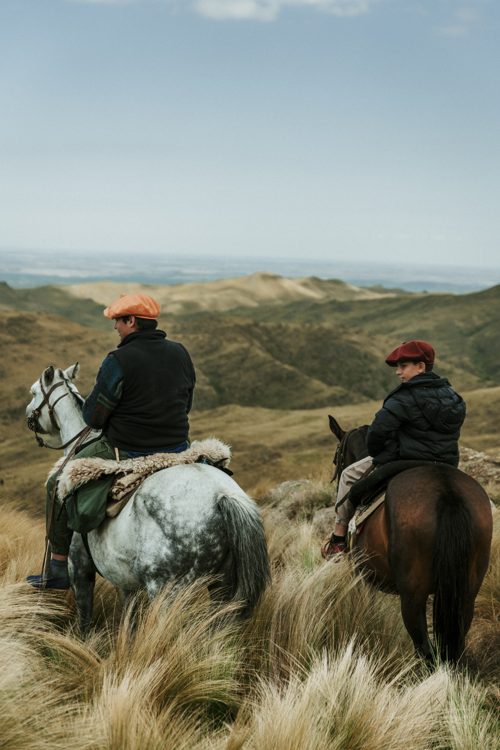 Two riders look over the valley from the ridge