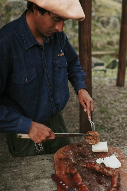 Matías slicing chorizo at the grill